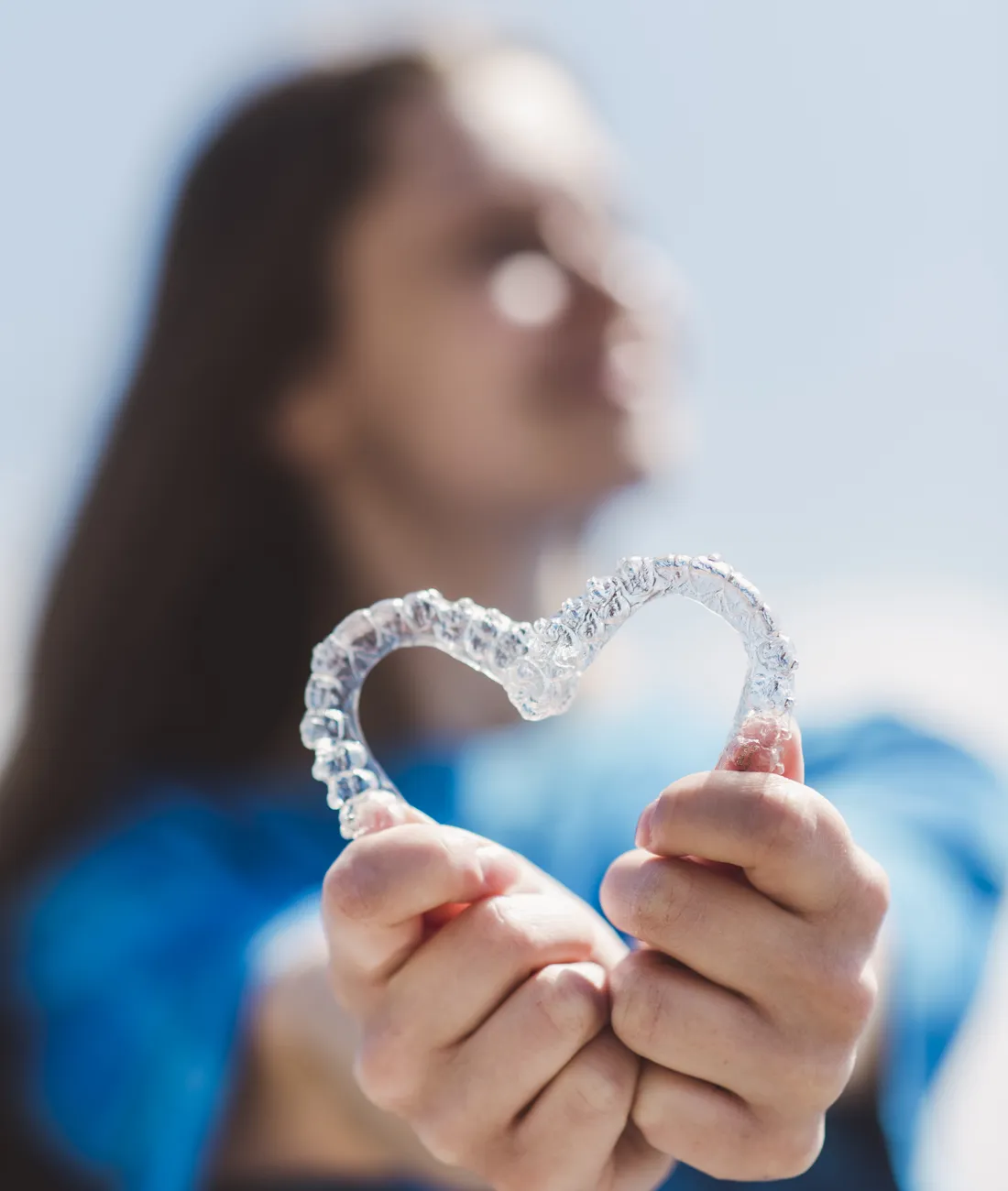 Paciente sosteniendo sus alineadores transparentes en forma de corazón